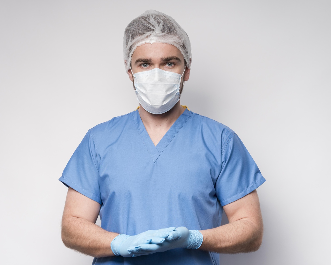 Male doctor in mask and gloves on gray background