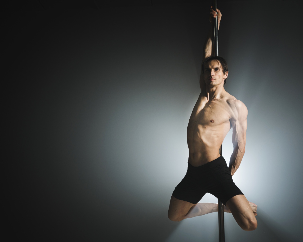 Man dancing on a pole on a gray background