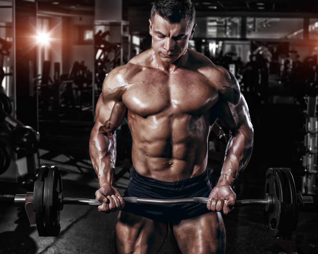 Мускулистый мужчина со штангой в руках в спортзале
