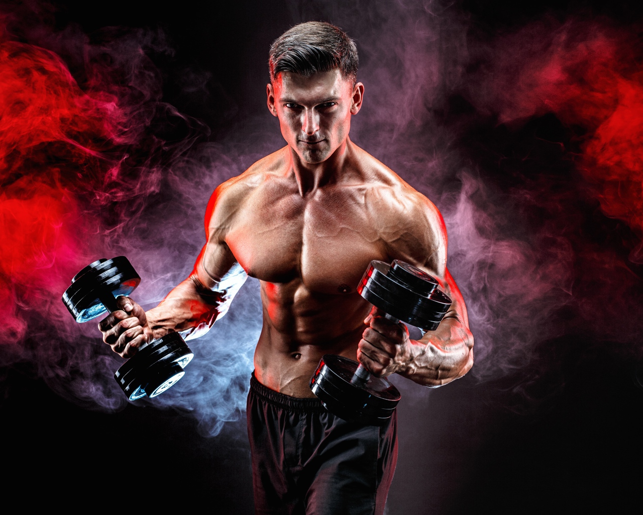 Мускулистый мужчина с гантелями в руках на черном фоне с дымом