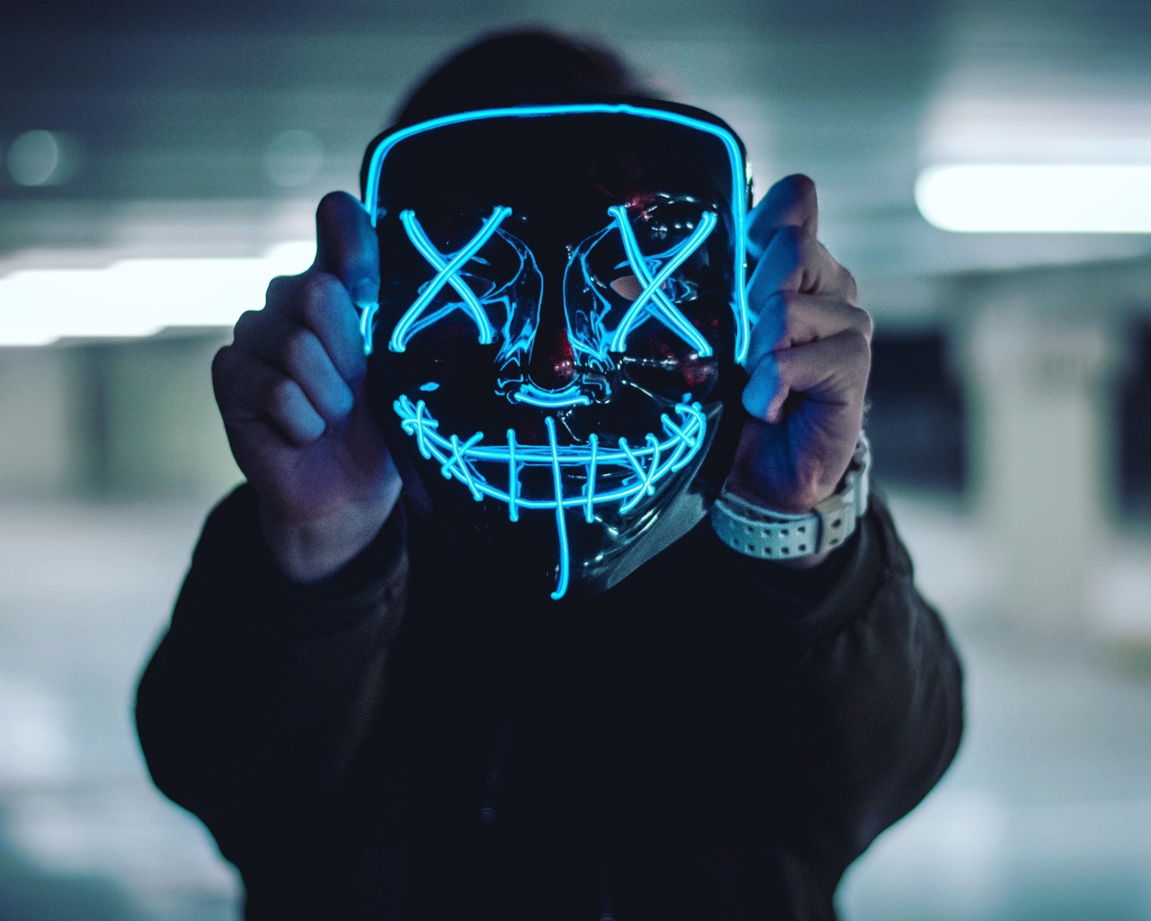 Неоновая маска анонима в руках у парня 