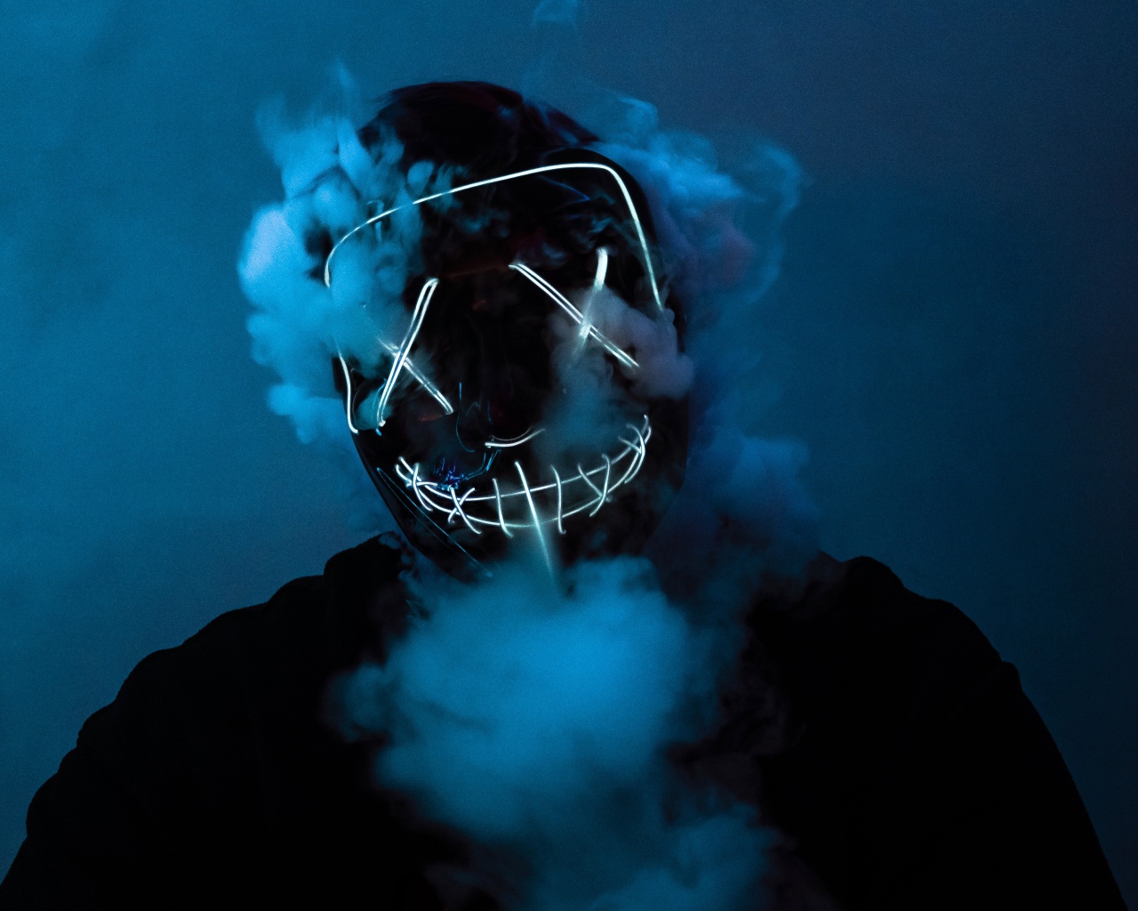 Дым идет из под неоновой маски анонимуса на лице у парня