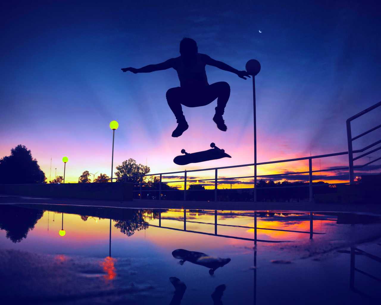 The guy jumps on a skateboard in the sunset