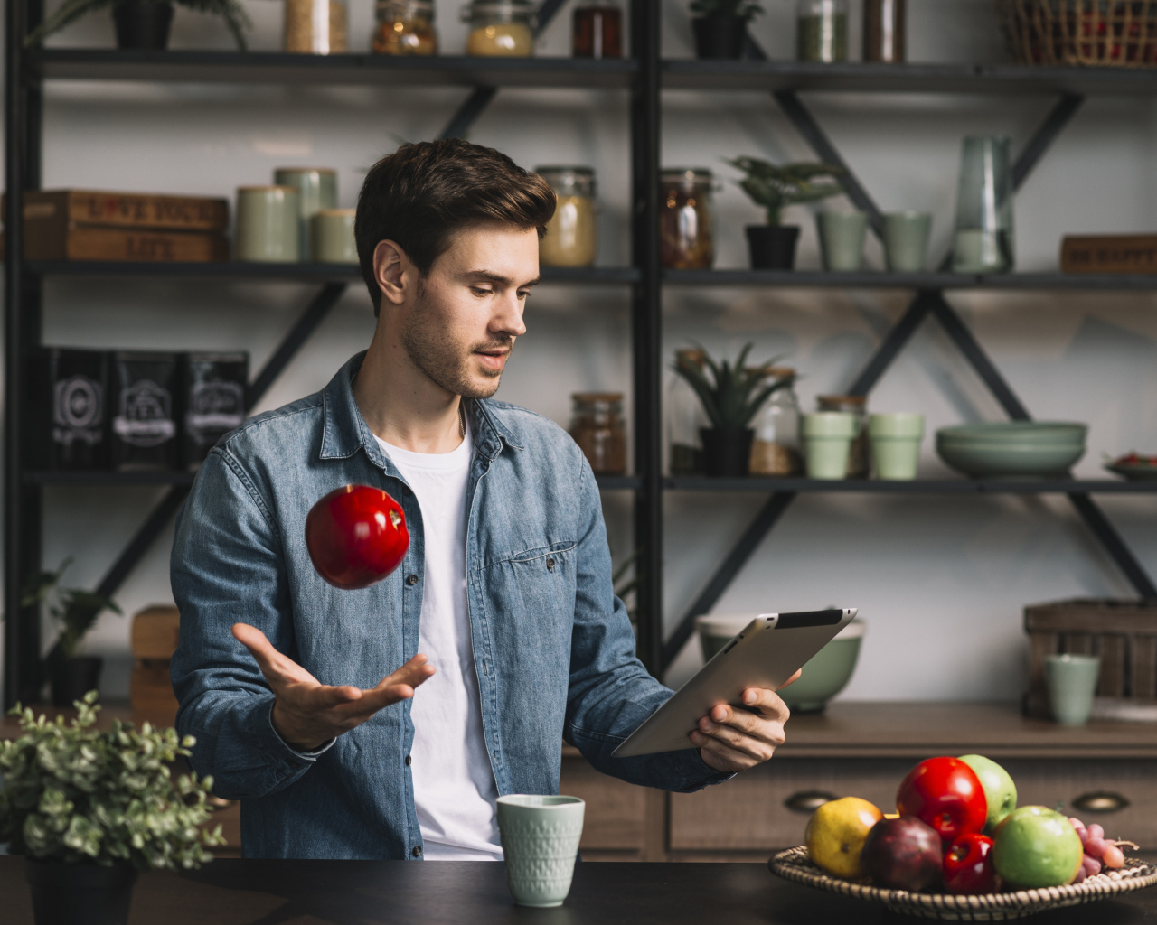 Молодой мужчина с планшетом и яблоком в руке 