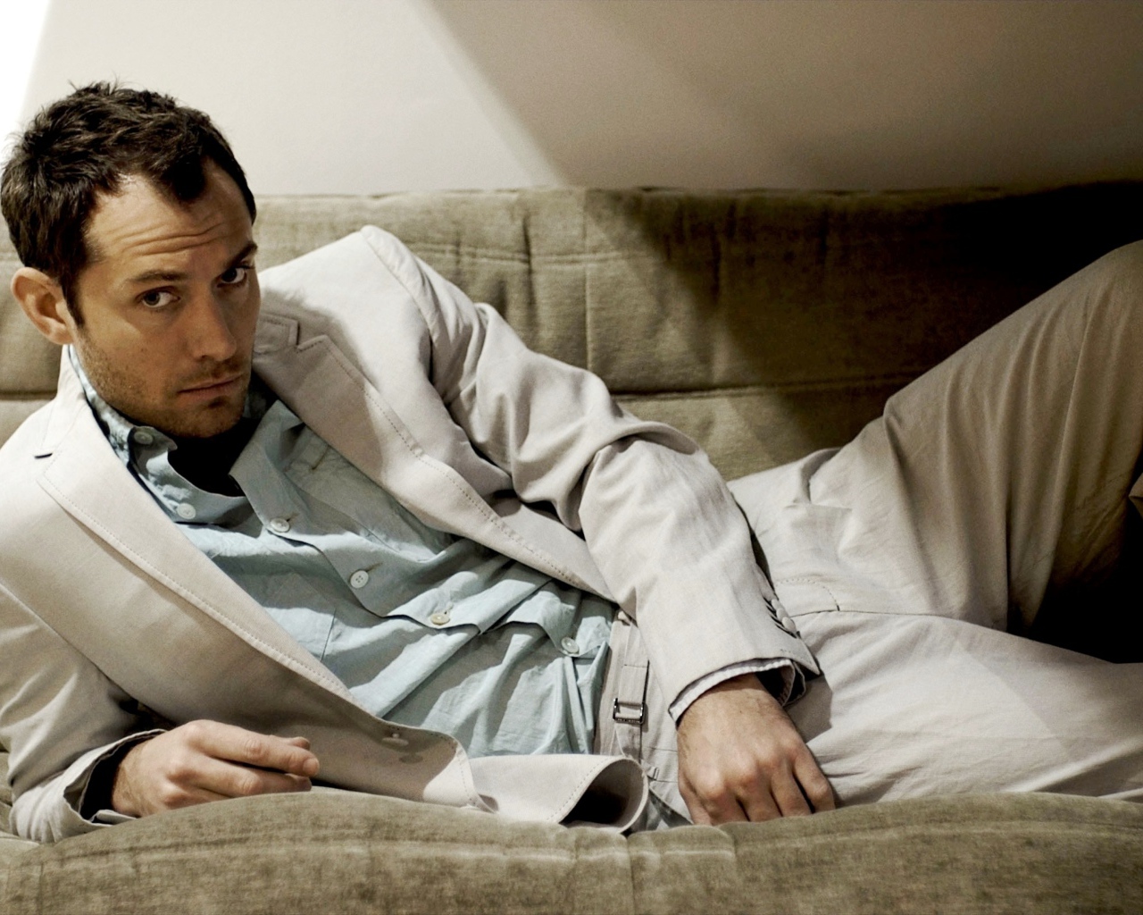 Британский актер Джуд Лоу в костюме лежит на диване