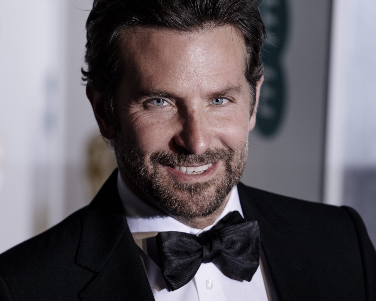 Улыбающийся актер Брэдли Купер в костюме