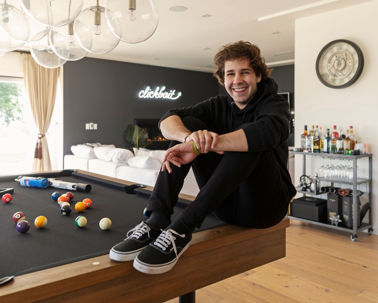 Молодой блогер, юморист  Дэвид Добрик сидит на столе