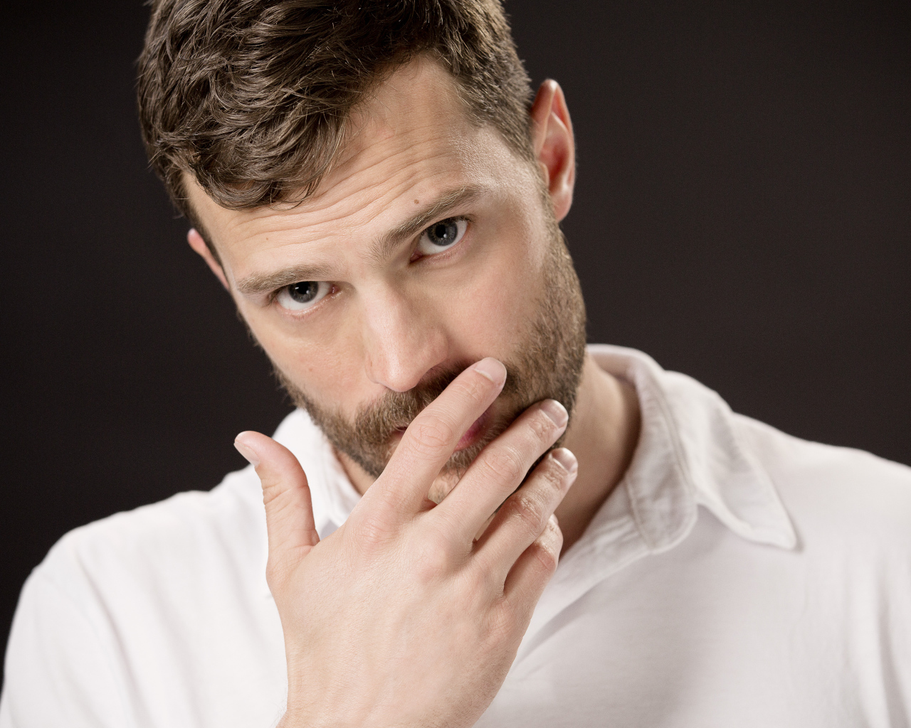 Молодой мужчина, актер Джейми Дорнан с рукой у лица