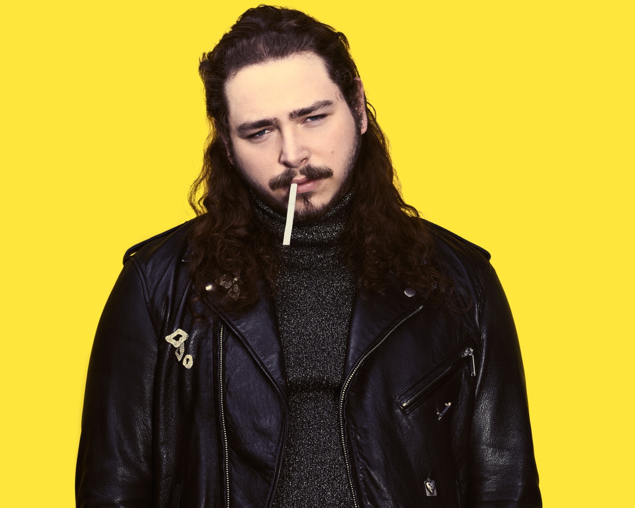 Американский рэпер Post Malone в черной куртке на желтом фоне