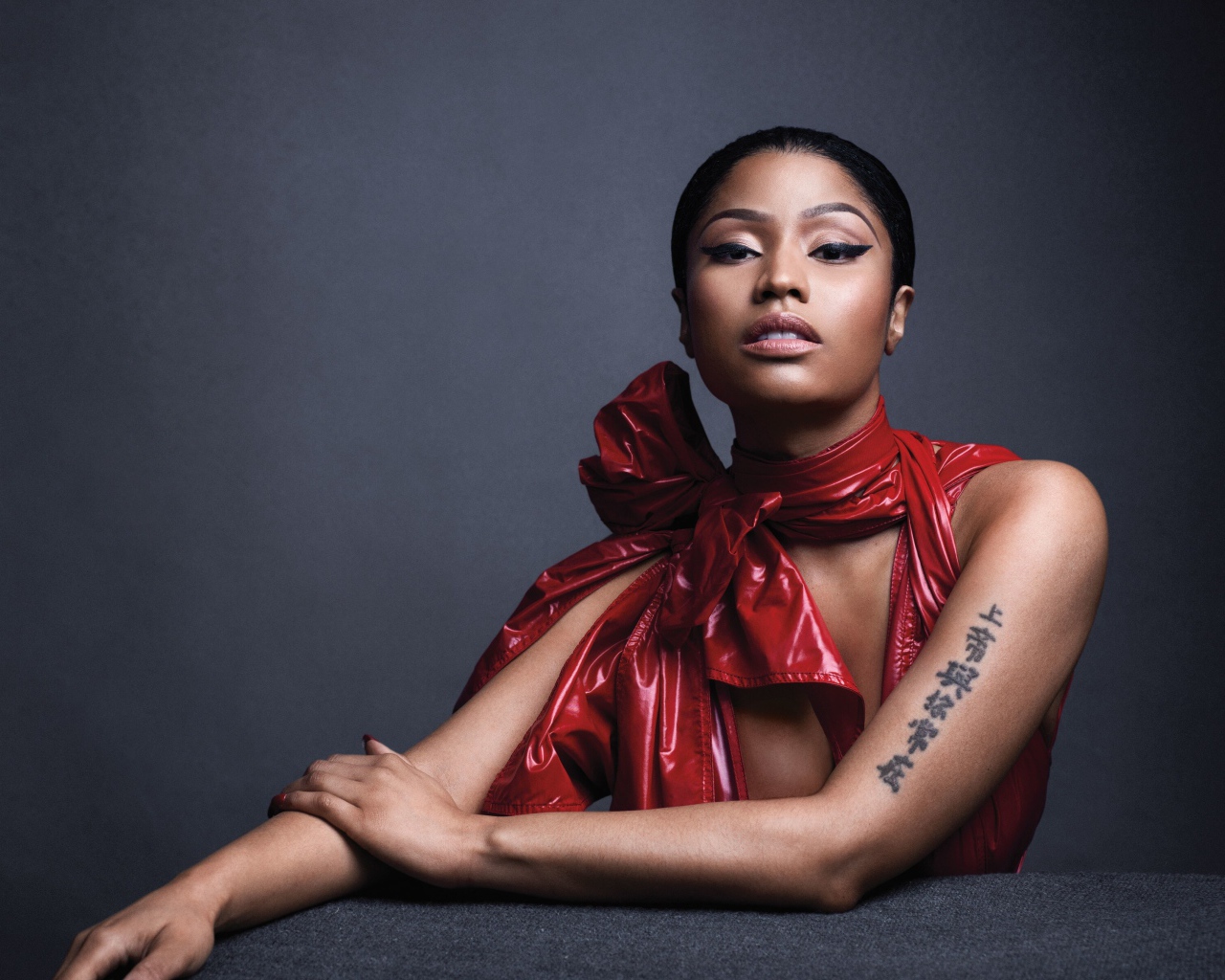 Американская певица, рэпер Ники Минаж  в красном наряде на сером фоне