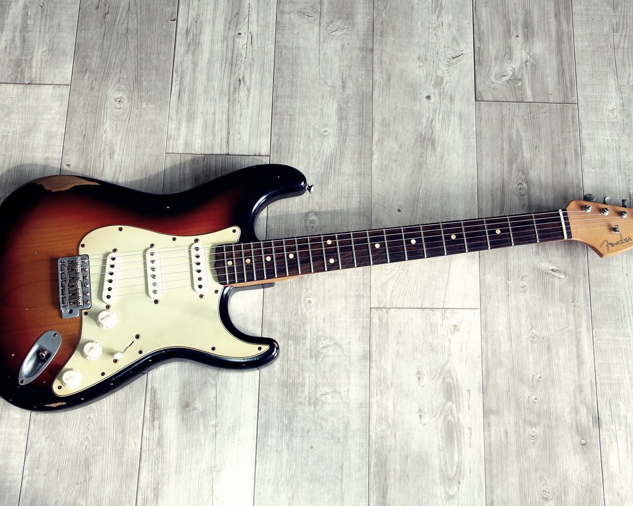 Электрогитара лежит на деревянном полу