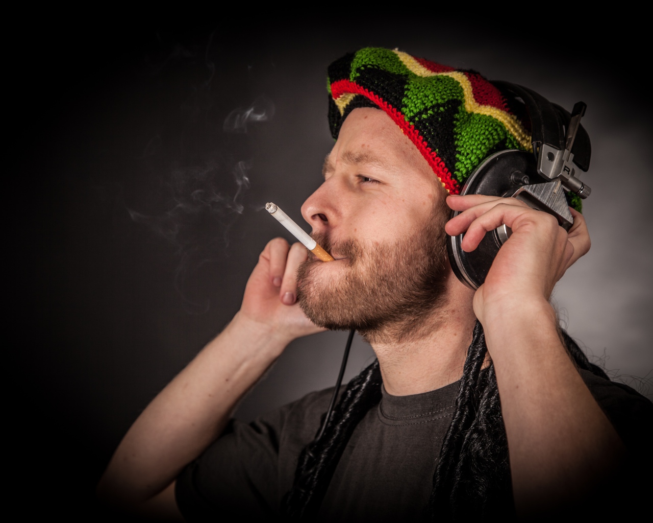 Мужчина растаман в наушниках с сигаретой 