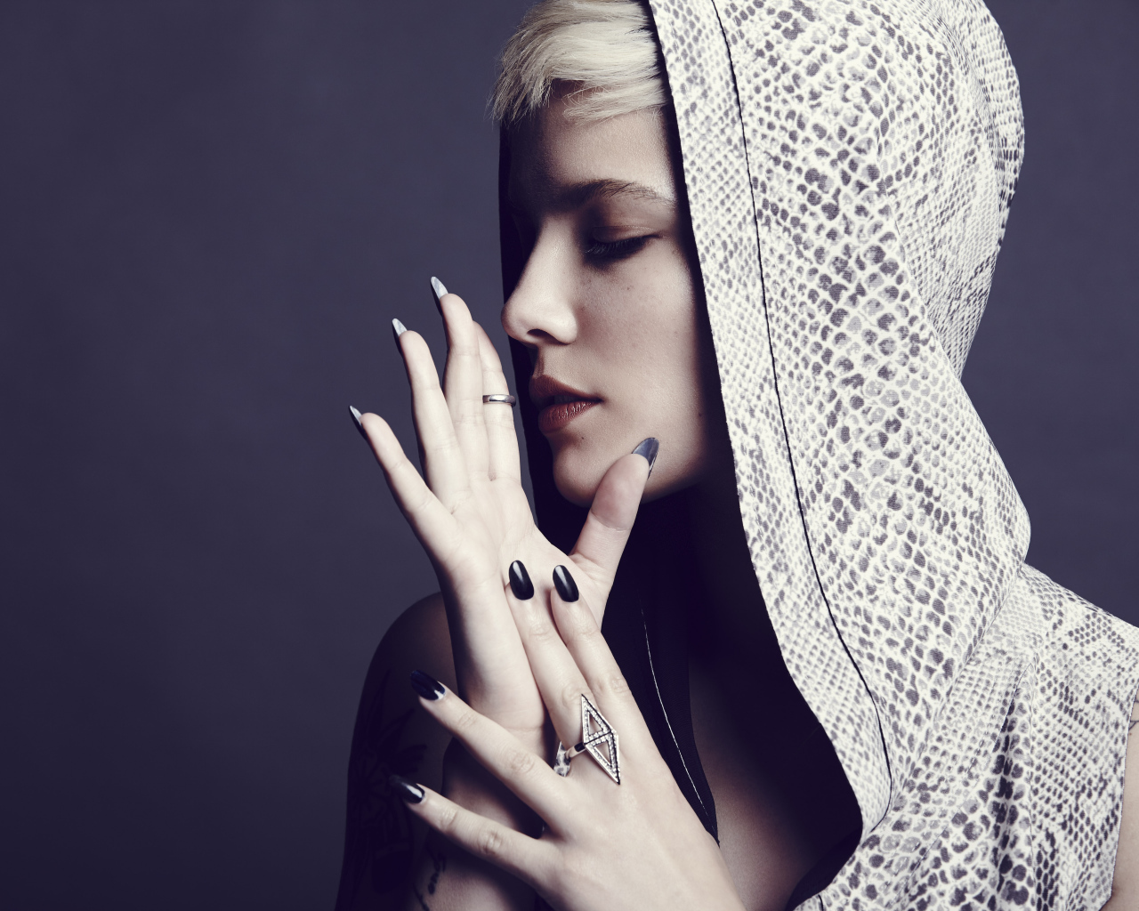 Певица Холзи в капюшоне на сером фоне