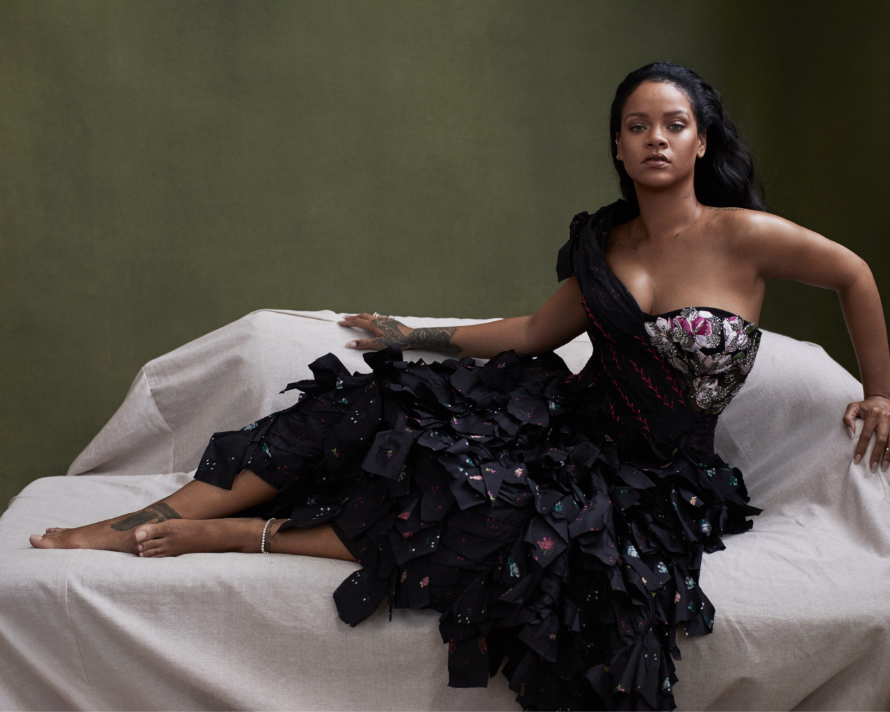 Певица Рианна в черном платье на диване 