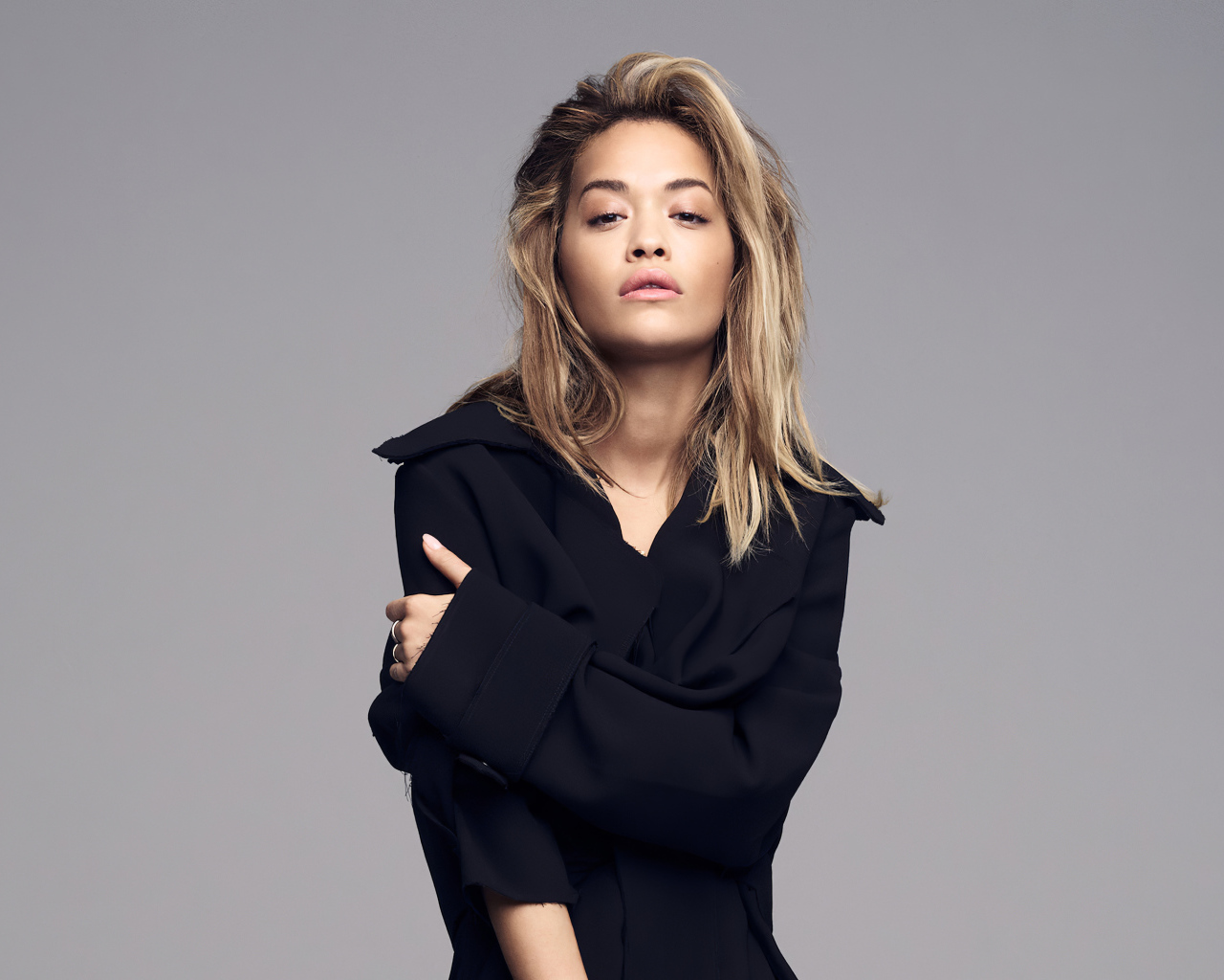 Певица Рита Ора в черном наряде на сером фоне