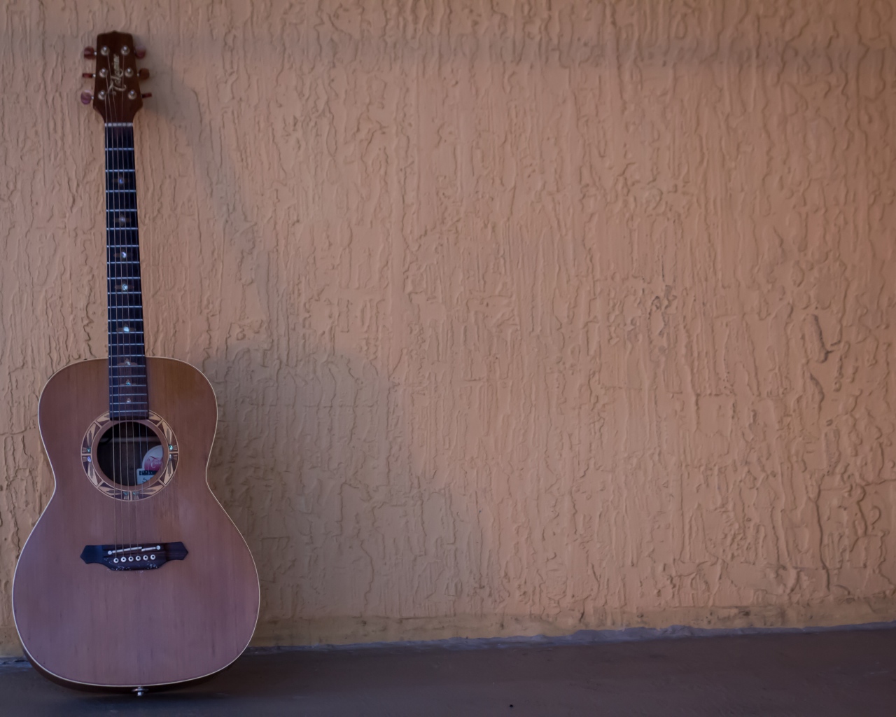 Шестиструнная гитара стоит у стены