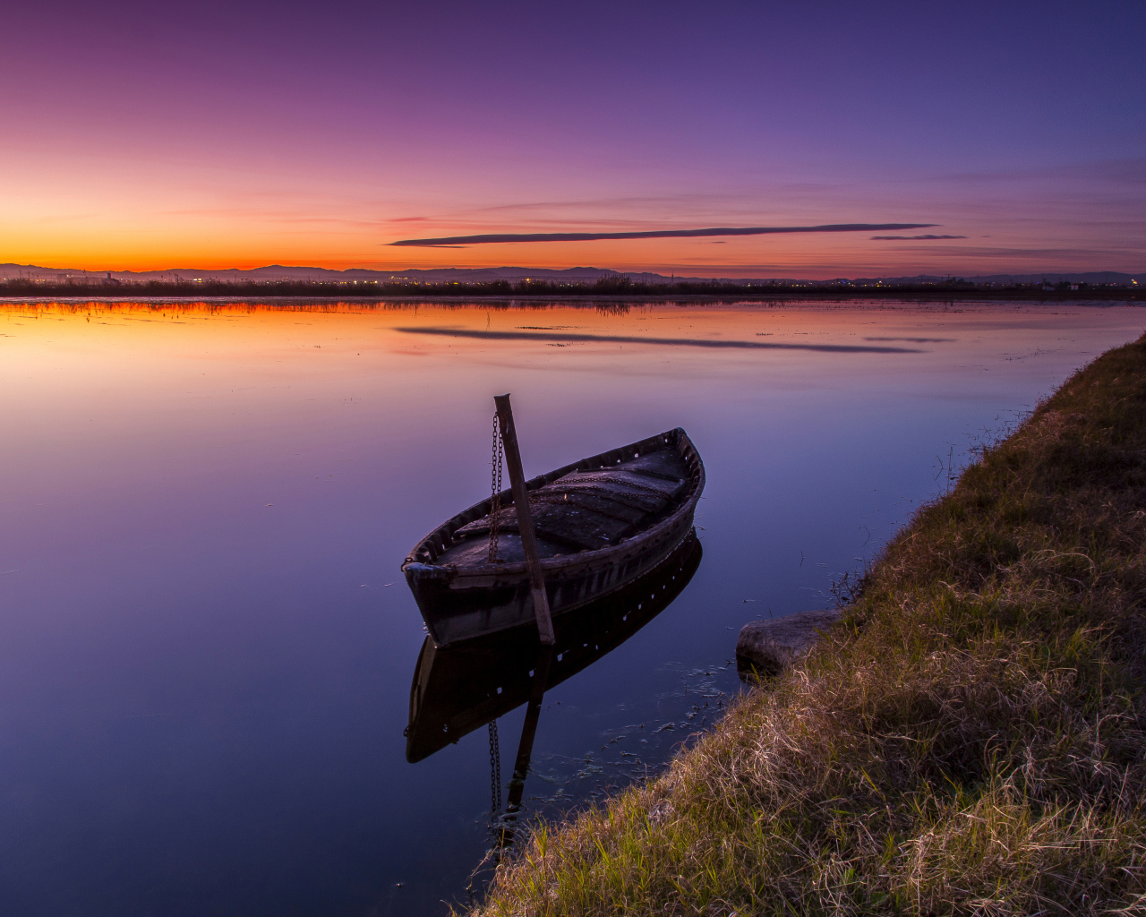 Старая лодка стоит в воде на закате солнца 