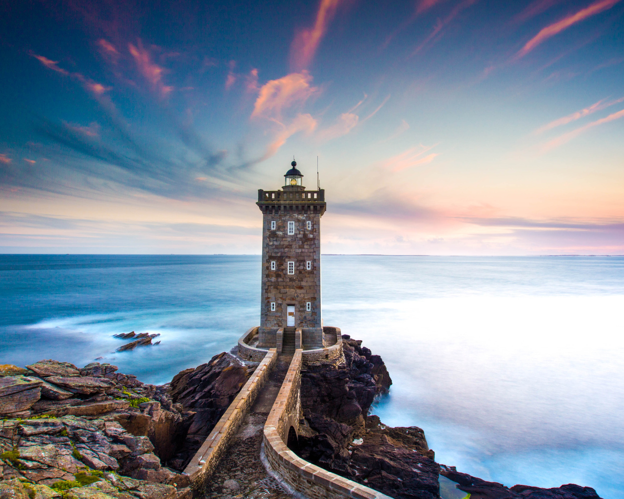 Большой маяк на фоне неба на берегу утеса 