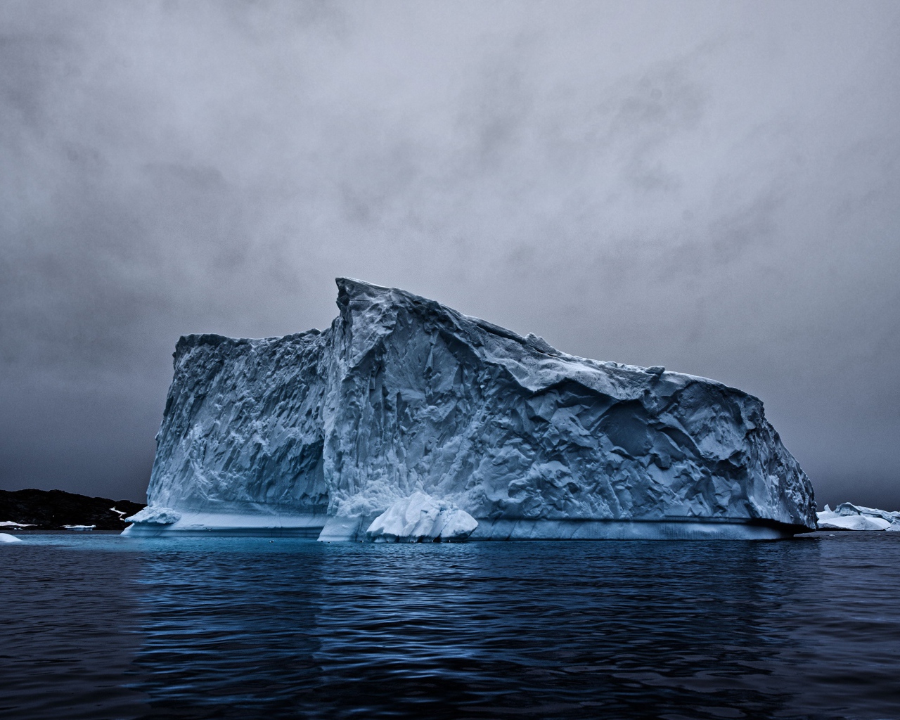 Большой айсберг в океане под пасмурным небом