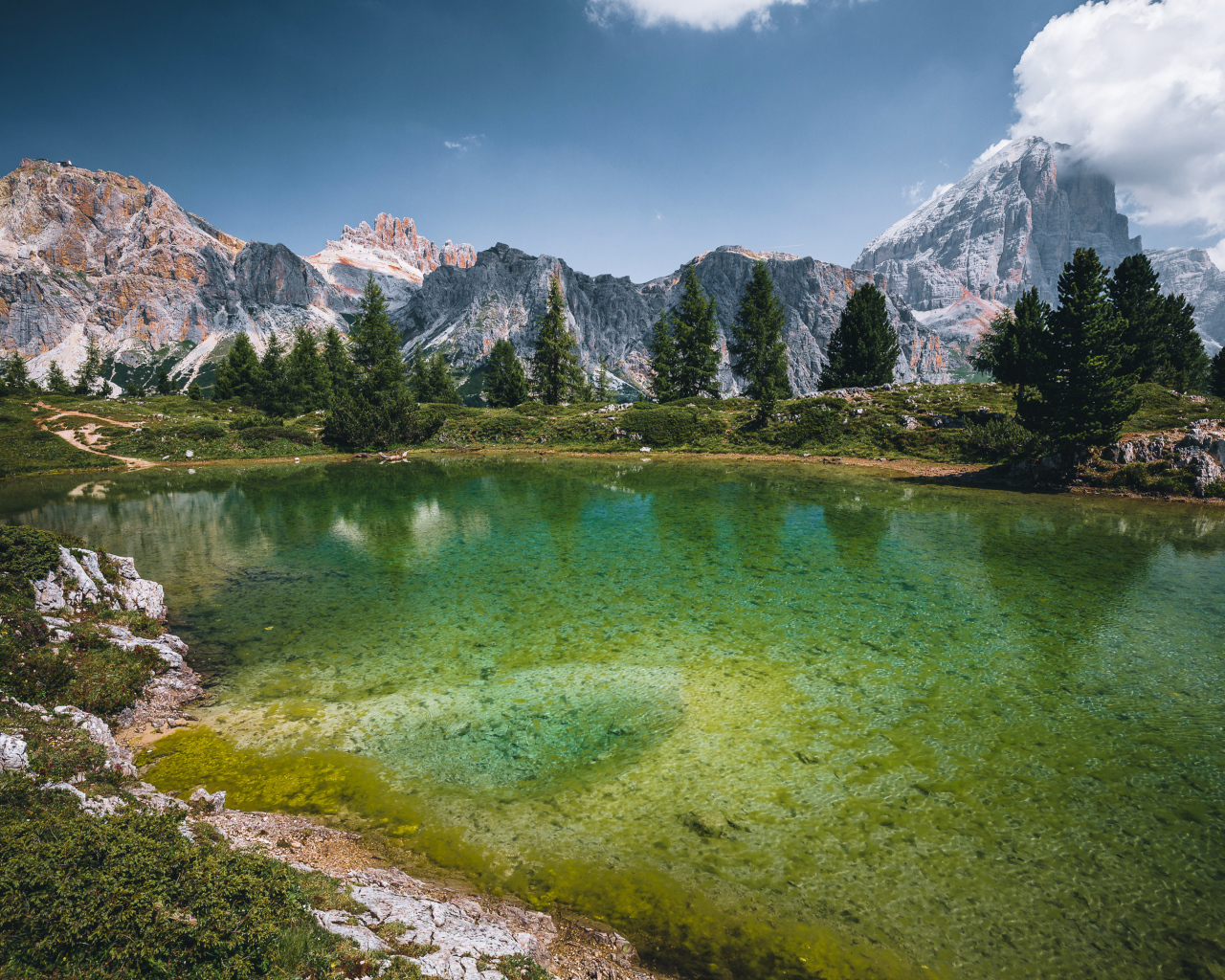 Озеро у заснеженных гор под небом с белыми облаками