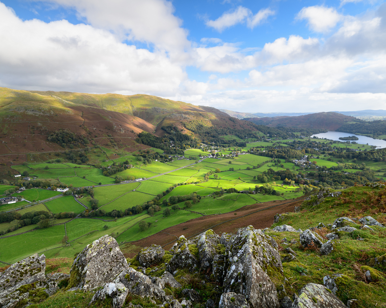 Вид на зеленые холмы под голубым небом с белыми облаками летом