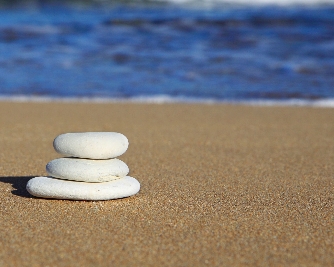 Круглые белые камни на желтом песке 