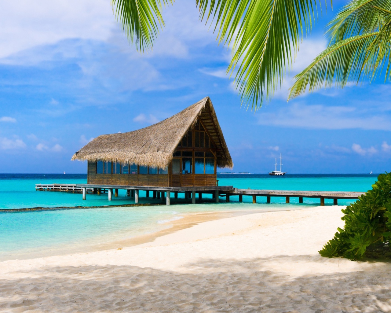 Дом на сваях на берегу тропического пляжа с белым песком