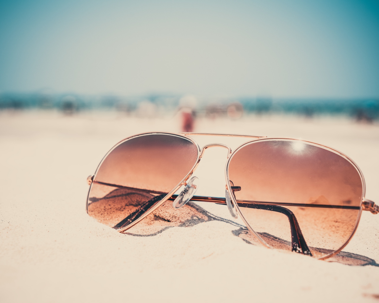 Солнечные очки лежат на горячем песке 