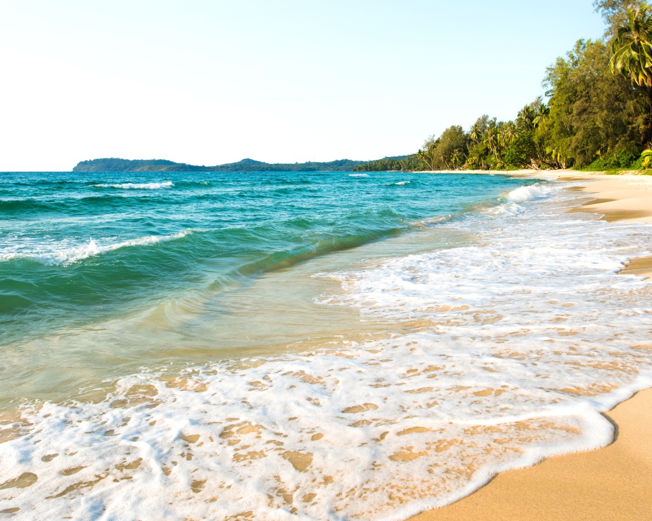 Белая пена на желтом песке тропического пляжа 