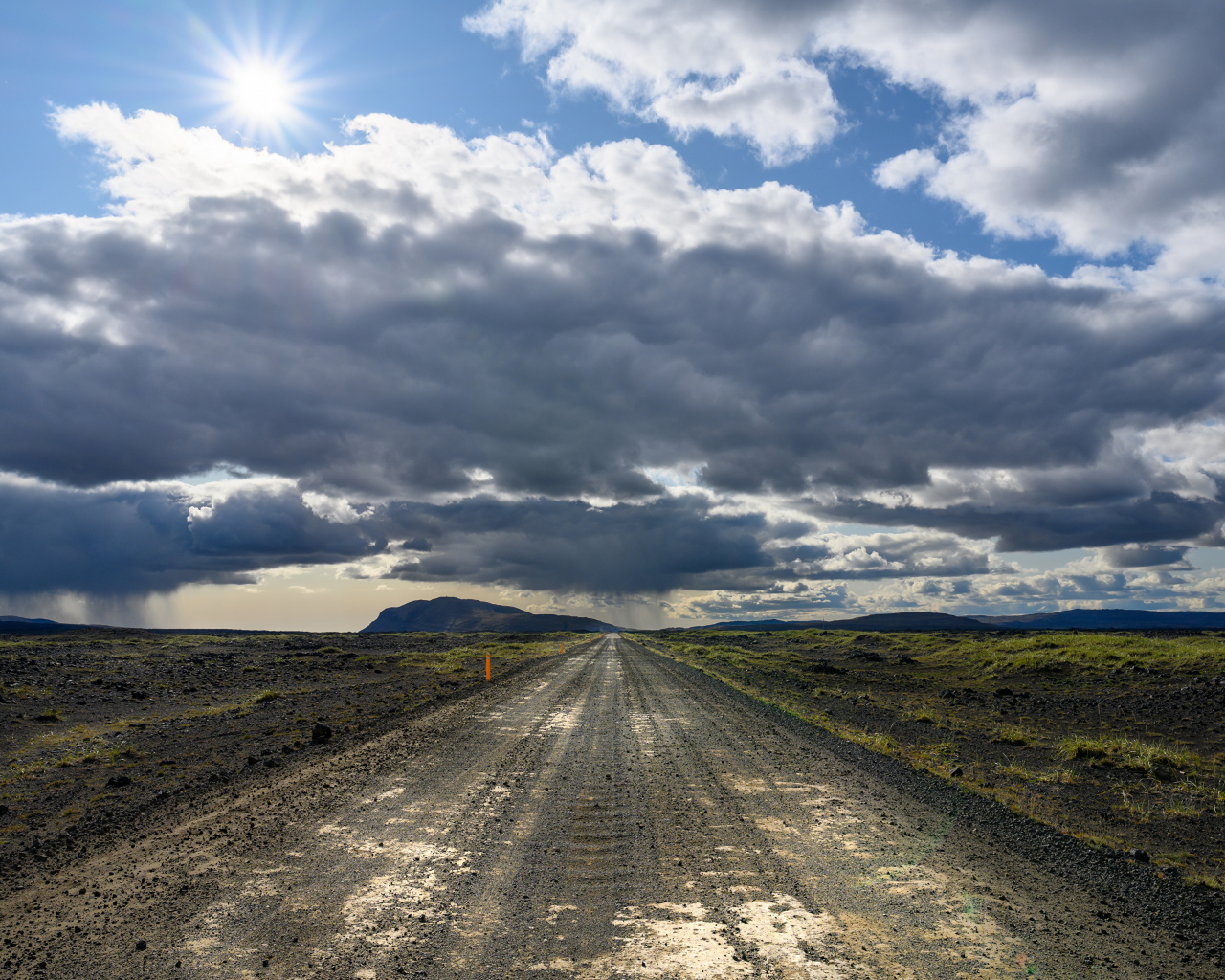Длинная дорога под голубым солнечным небом с белыми облаками летом
