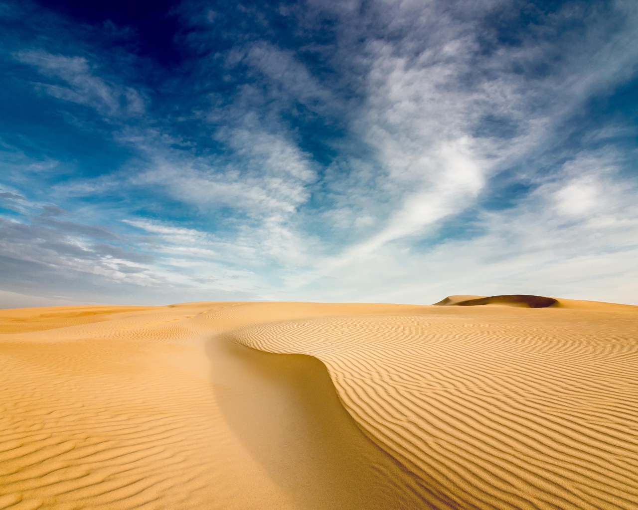 Песчаная дюна под голубым небом с белыми облаками 