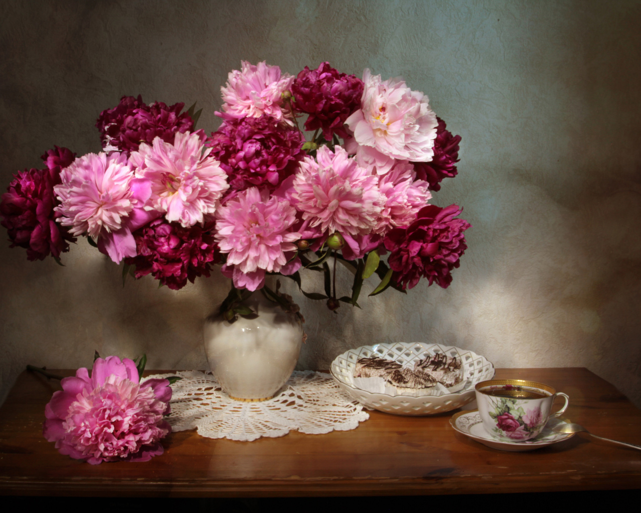 Большой букет розовых пионов в вазе на столе 