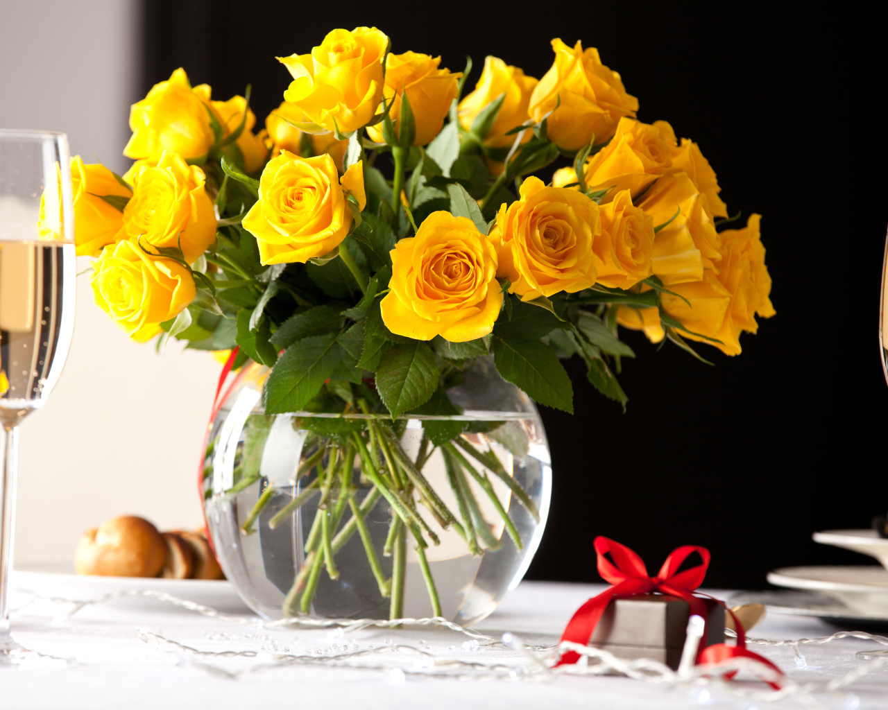 Большой букет желтых роз в вазе на столе с фужерами