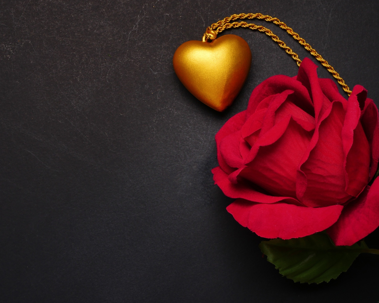 Искусственная красная роза с кулоном на сером фоне