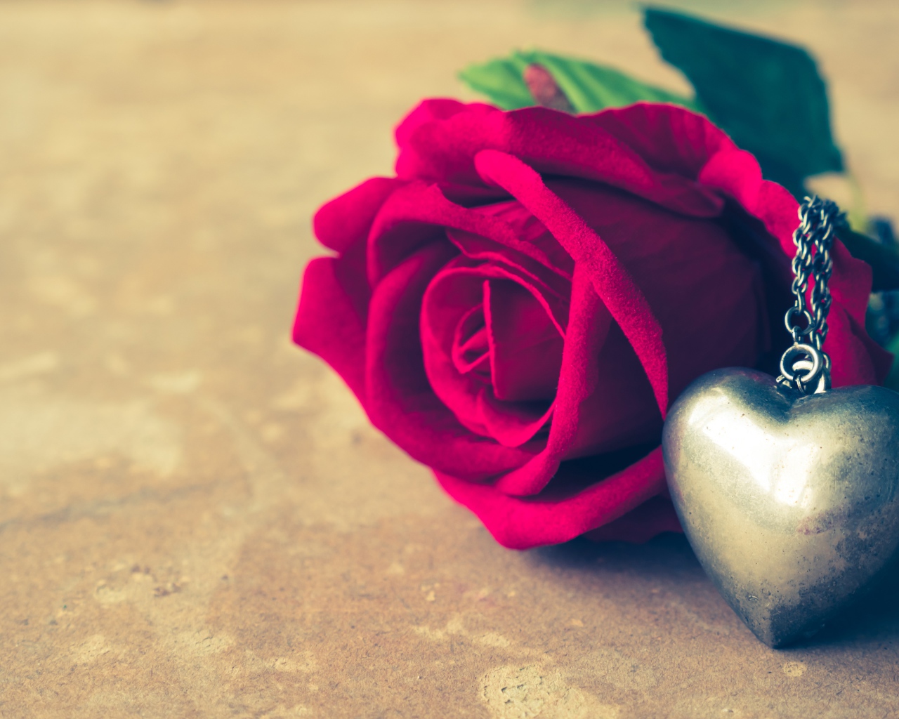 Искусственная роза с кулоном на столе