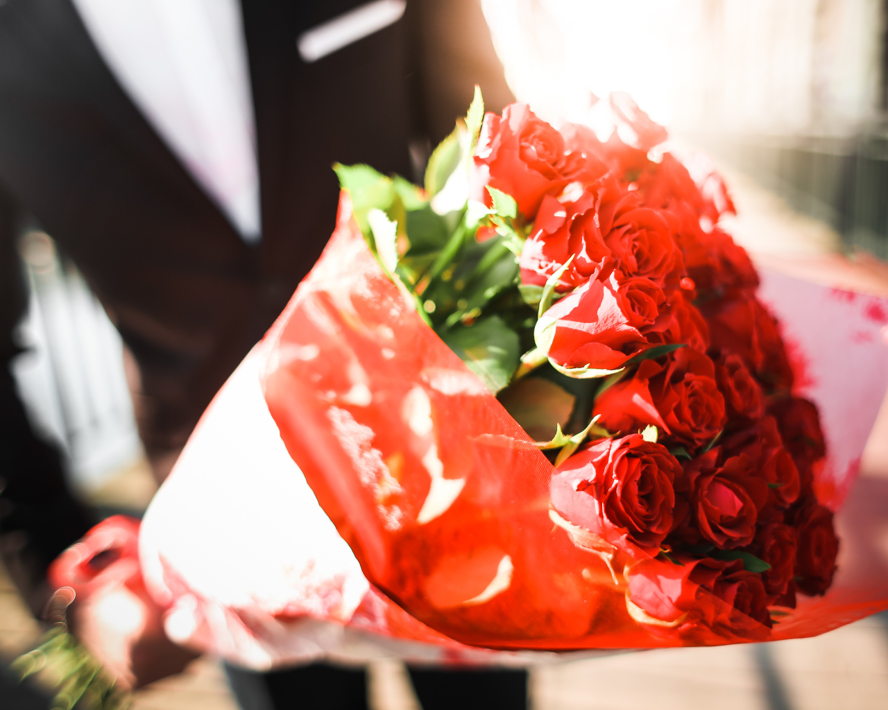 Большой красивый букет красных роз в руках мужчины 