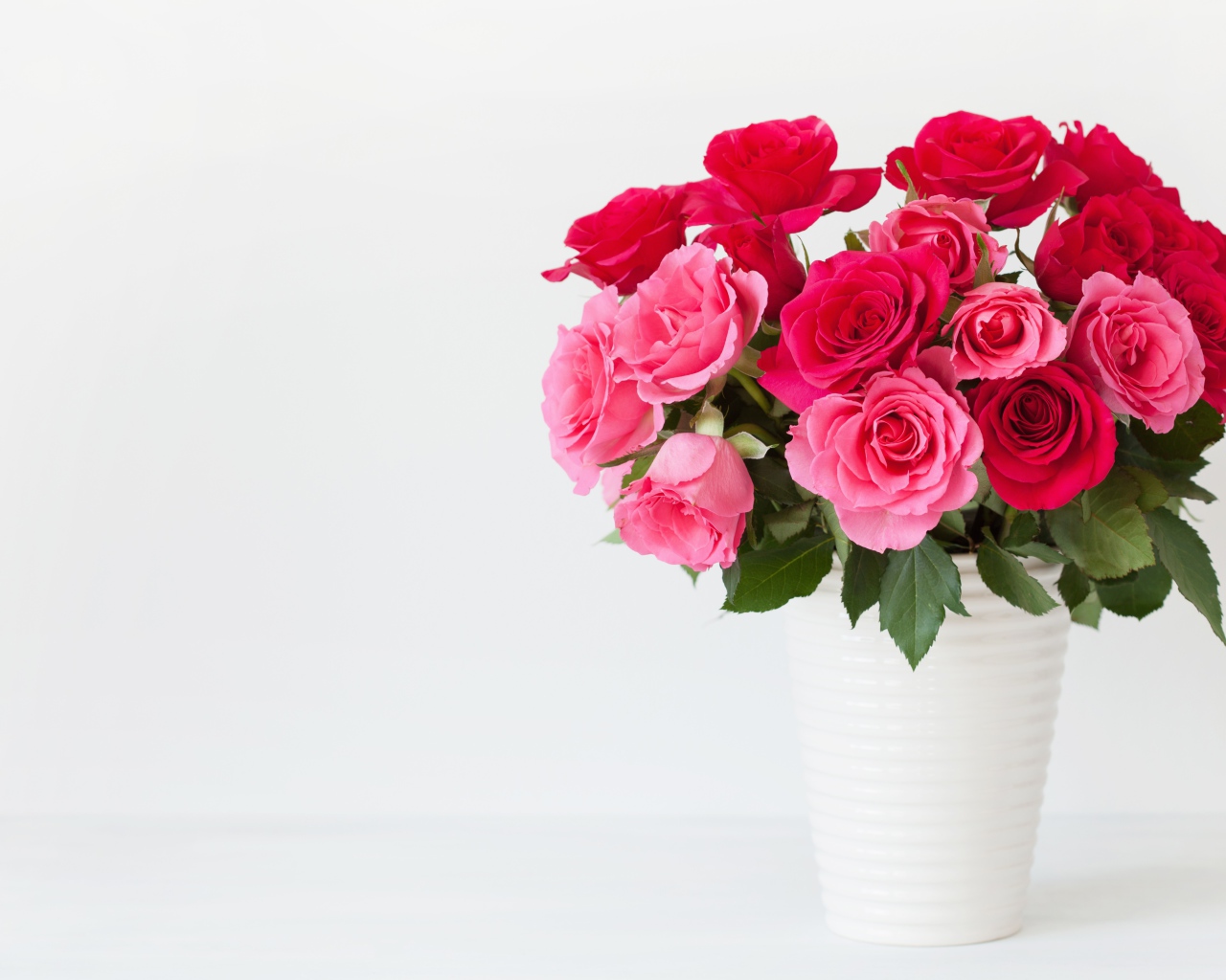 Букет красивых розовых роз в белой вазе на белом фоне