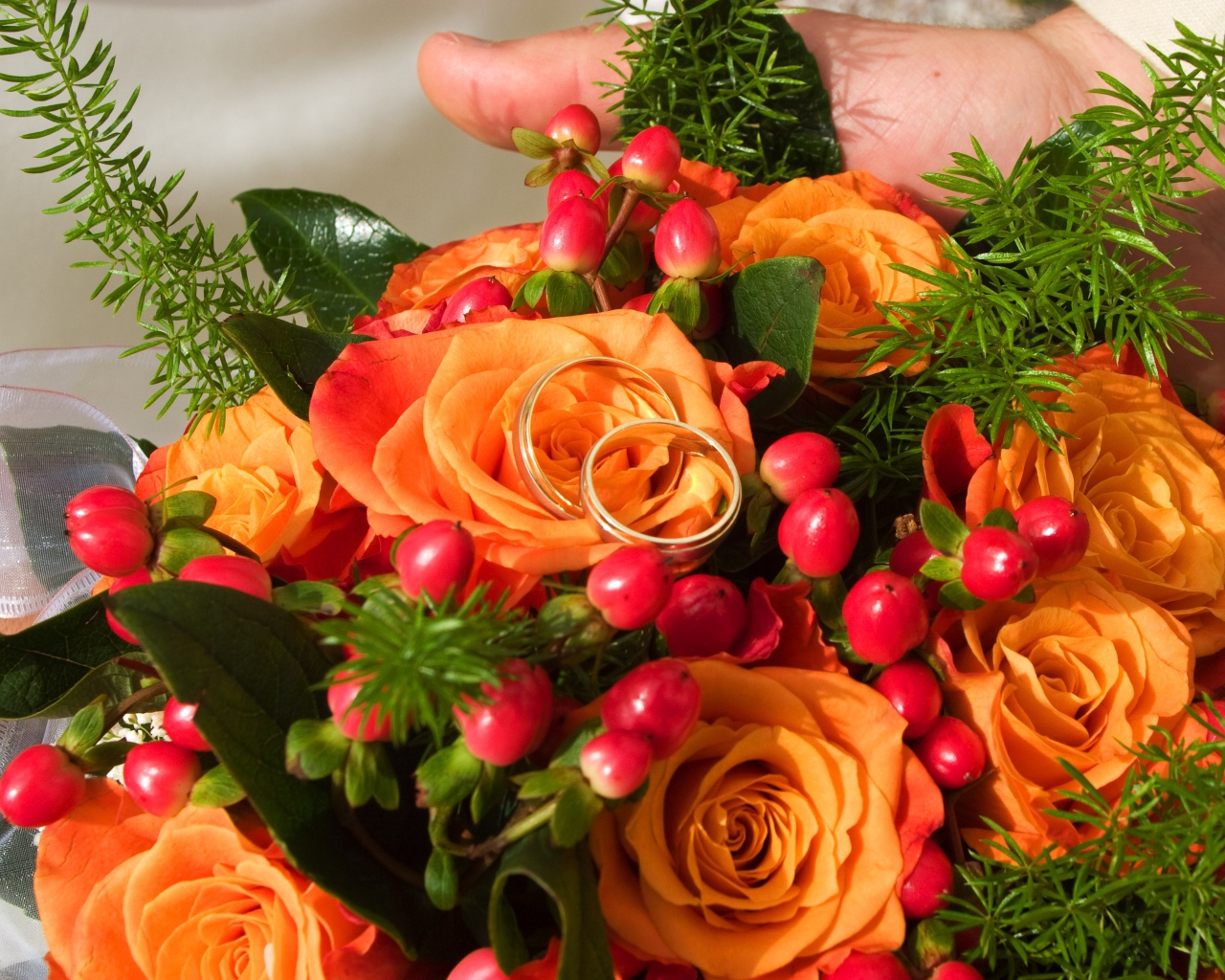 Букет оранжевых роз с красными ягодами и обручальными кольцами