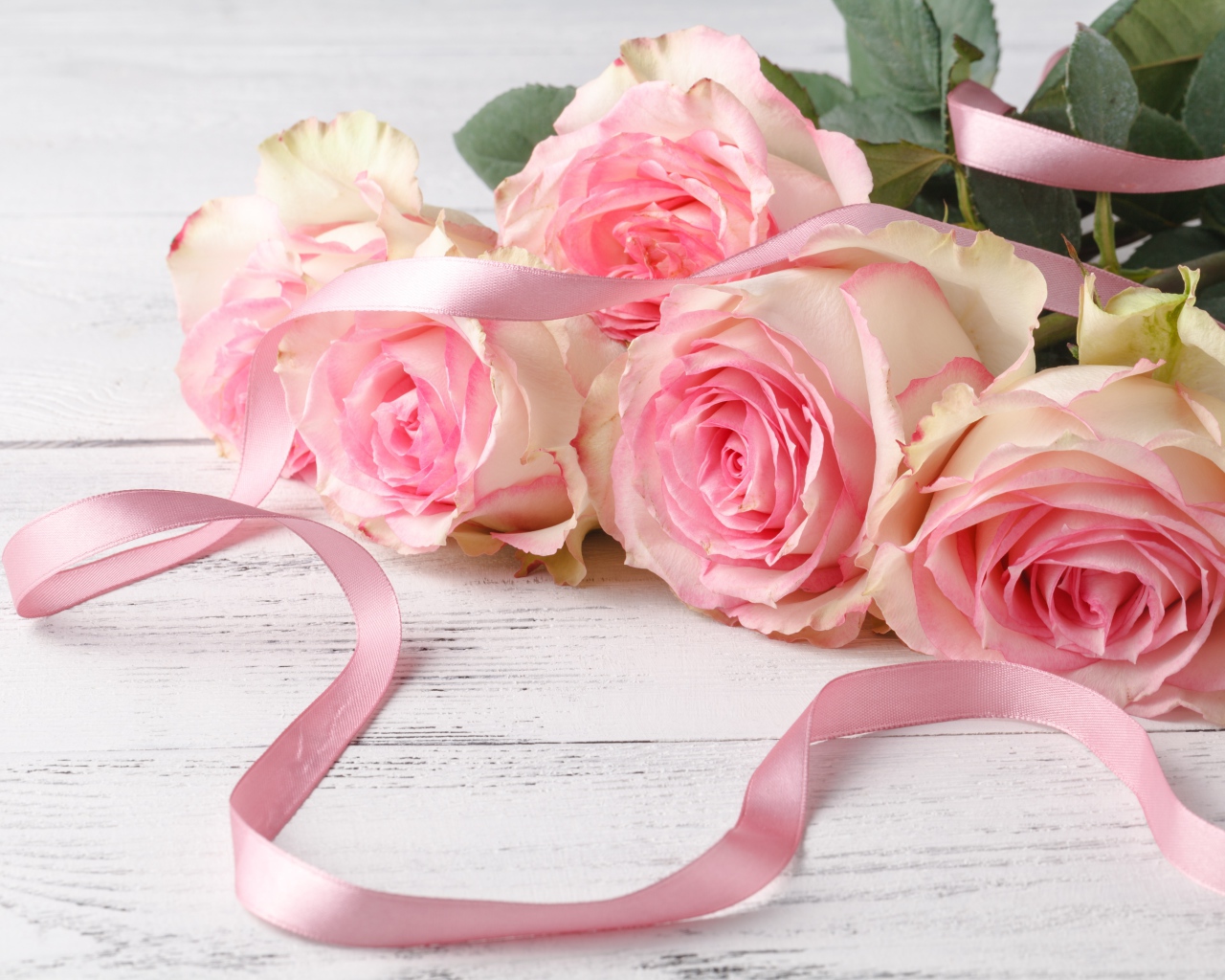 Букет розовых роз с лентой на белом столе 