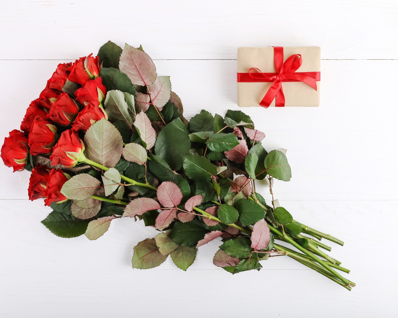 Bouquet of prickly red roses with a gift on a white background