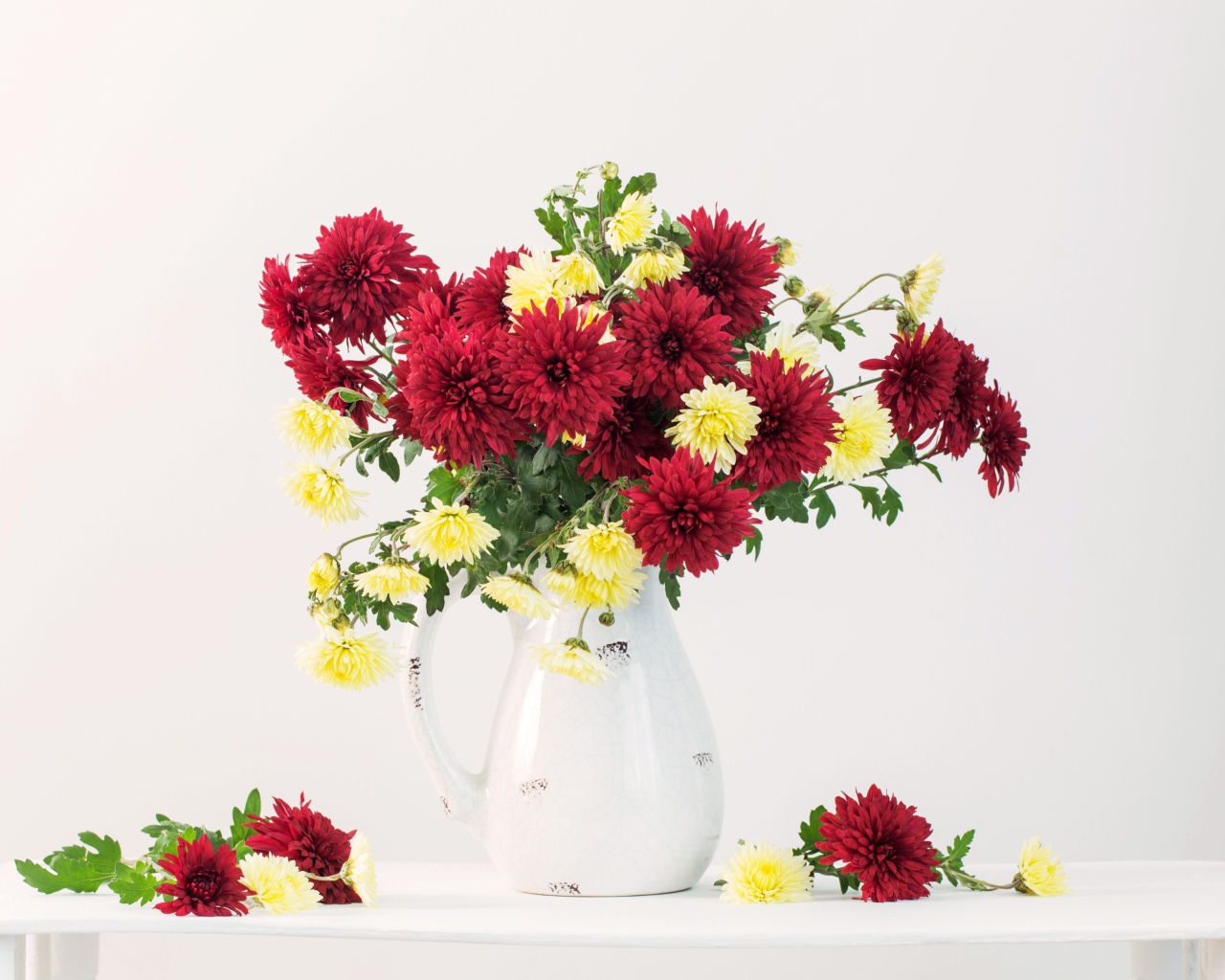 Букет красных и желтых хризантем в вазе на белом фоне