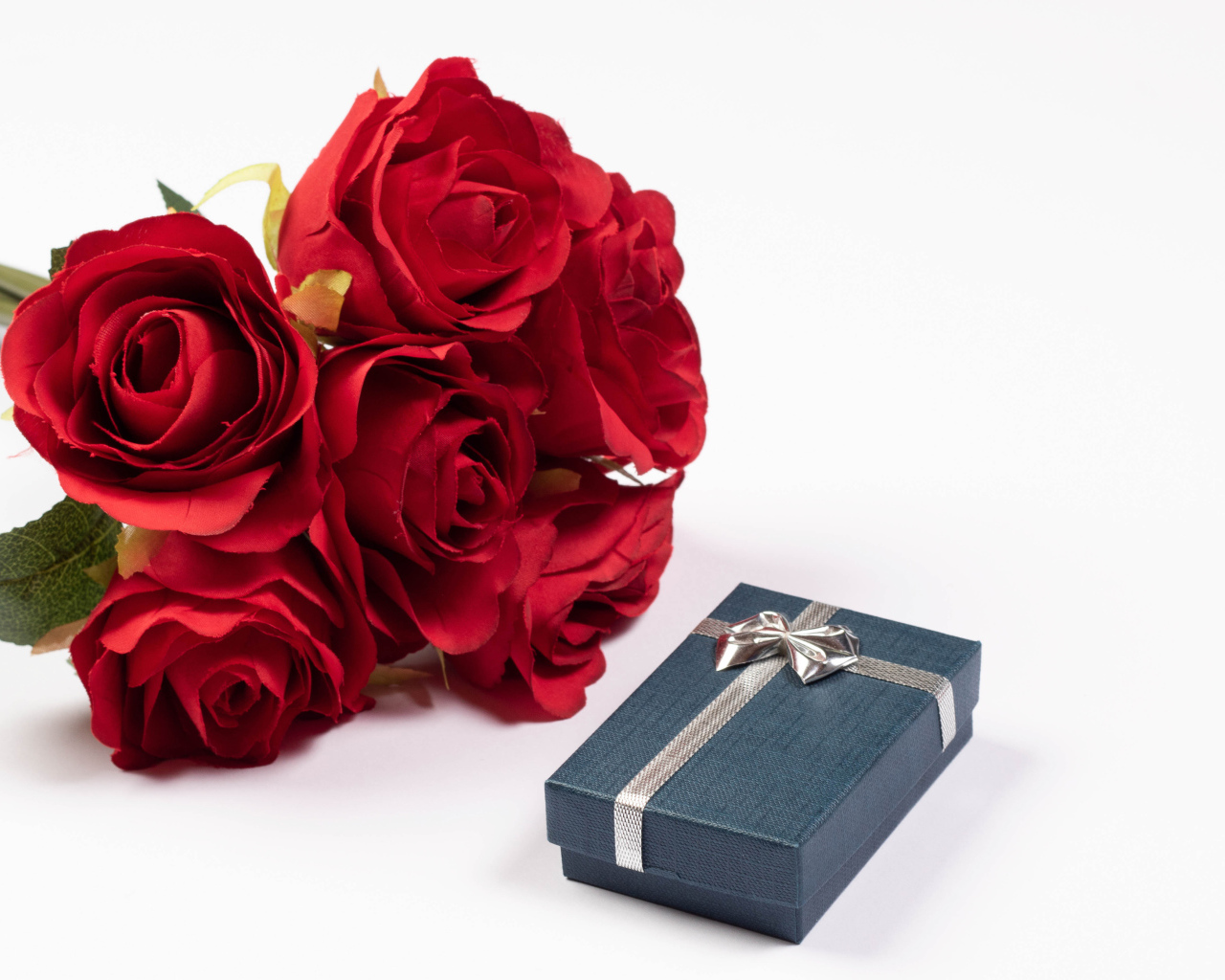 Букет красных искусственных роз с подарком на белом фоне