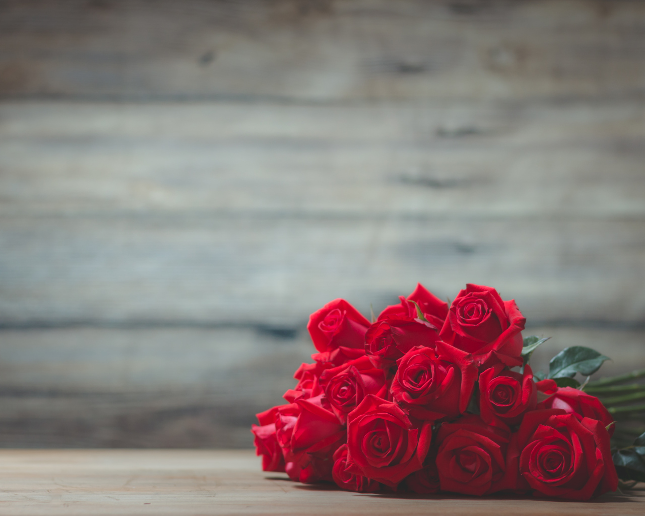 Букет красных роз на фоне деревянной стены 