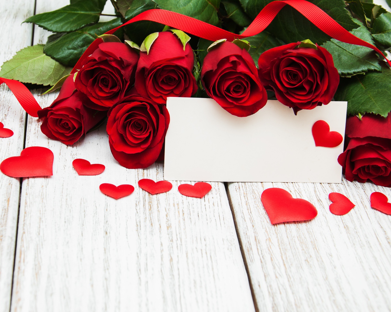 Букет красных роз на столе с сердечками и открыткой