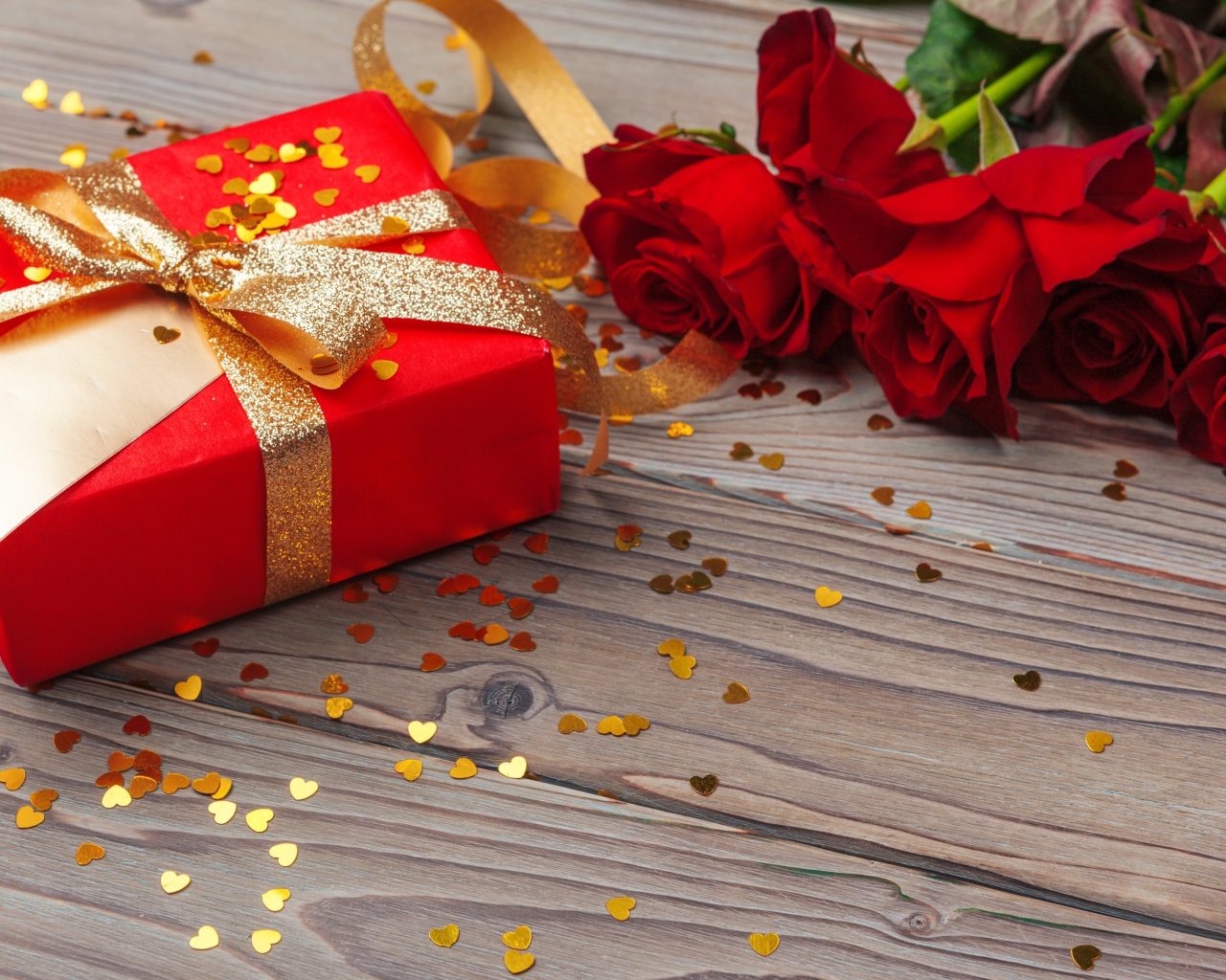 Букет красный роз с большим подарком на столе