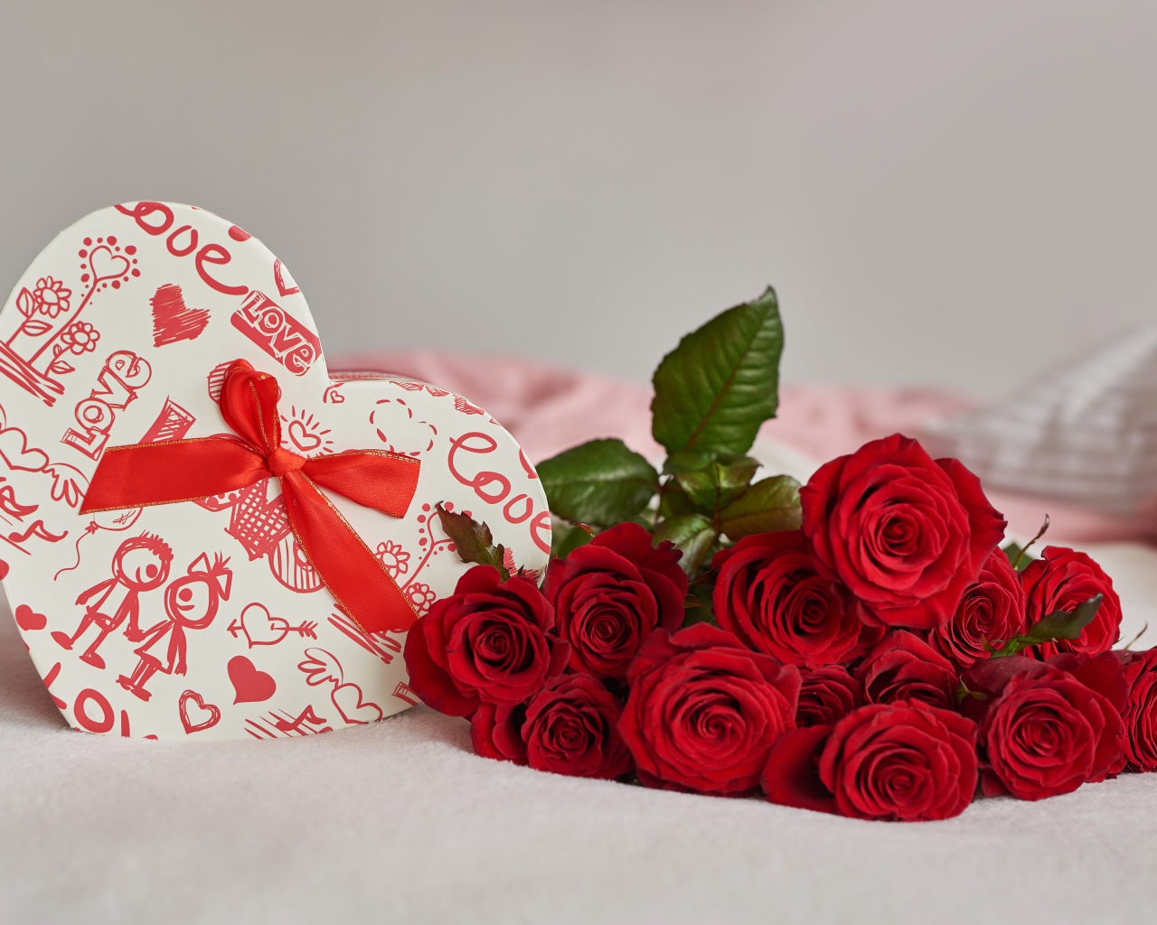 Букет красных роз с коробкой в форме сердца на кровати 