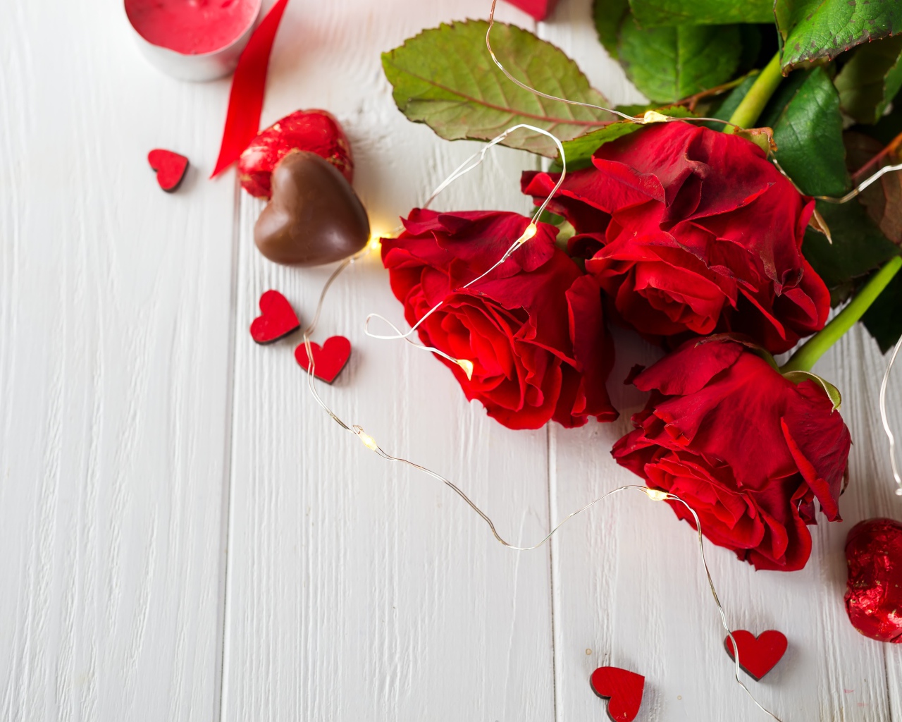 Букет красных роз с конфетами на столе