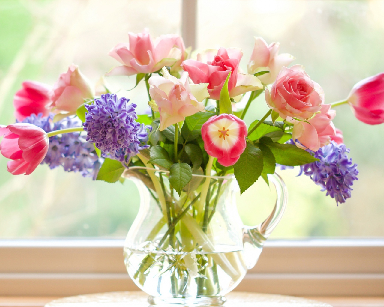 Букет роз, тюльпанов и гиацинтов в стеклянной вазе у окна