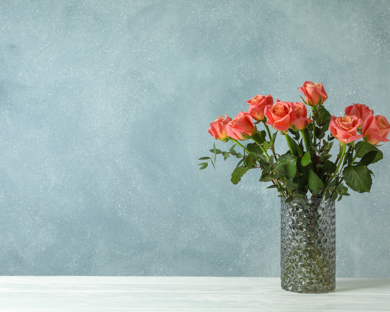 Букет роз в стеклянной вазе на сером фоне