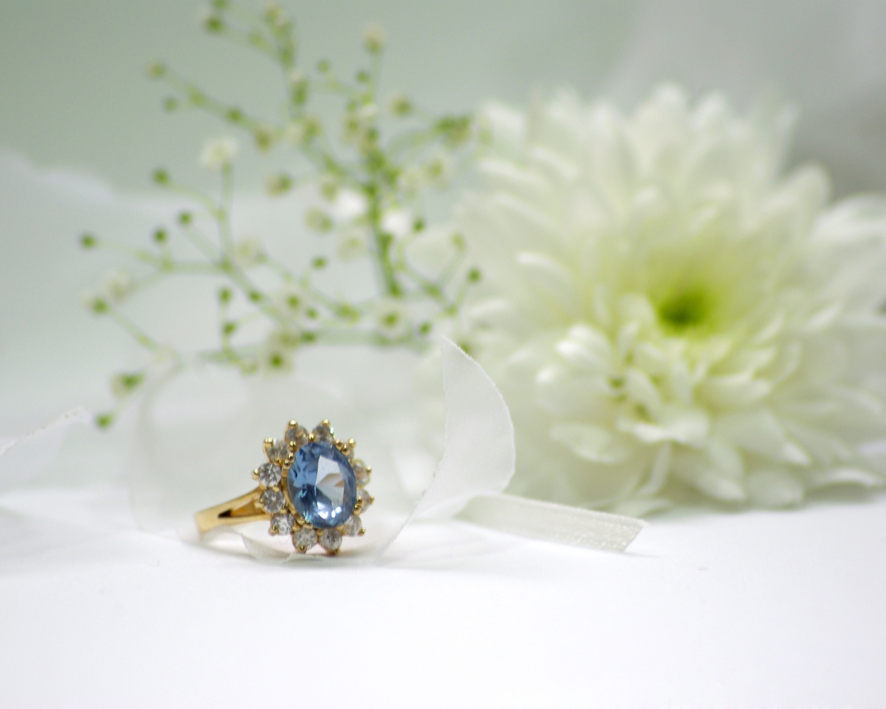 Дорогое кольцо с камнем на столе с белым цветком